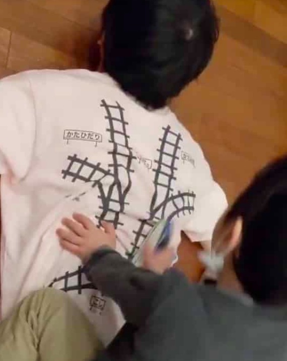 father designs a t-shirt with train track for son to do back massage